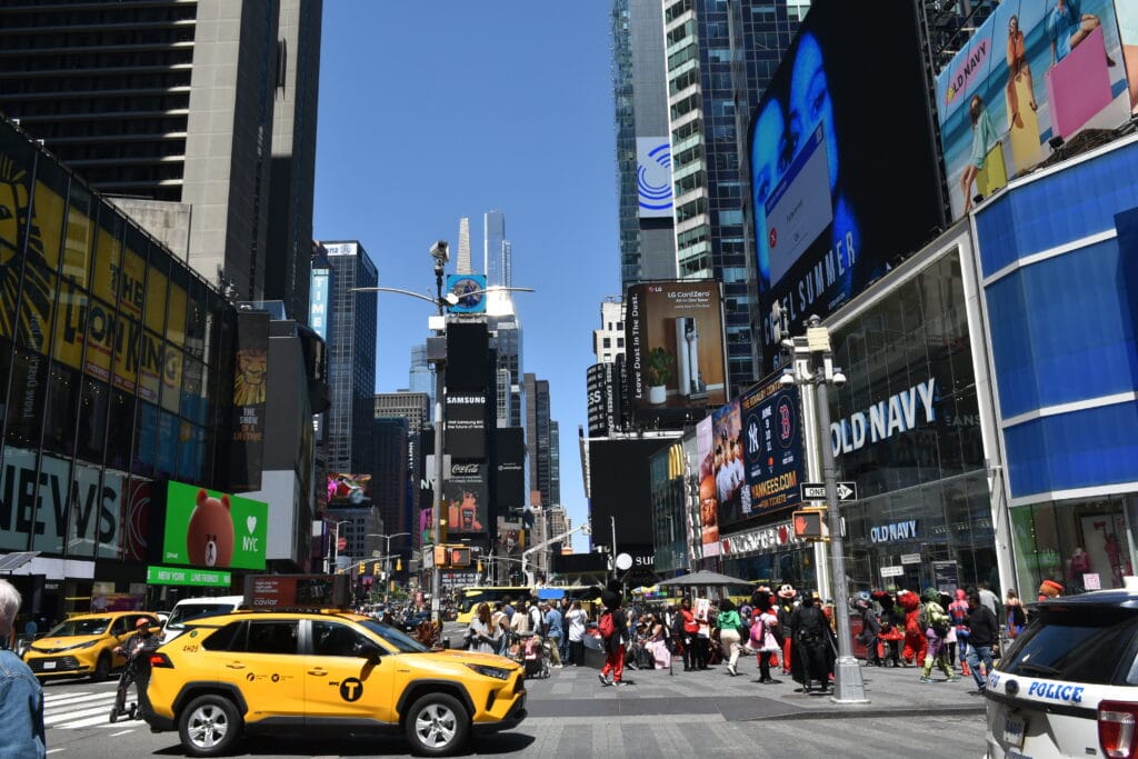 Busy Times Square, one of the most vibrant neighbourhoods in New York, buzzes with yellow taxis, crowds of people, and tall buildings covered in bright billboards.