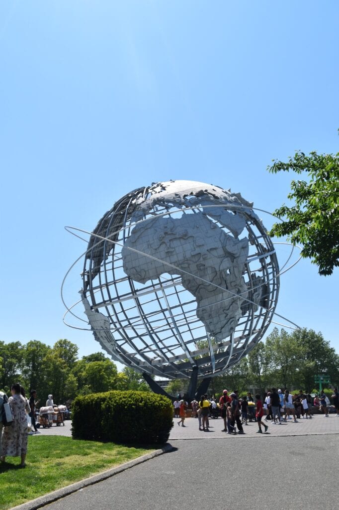 A large metal globe in the middle of a park.