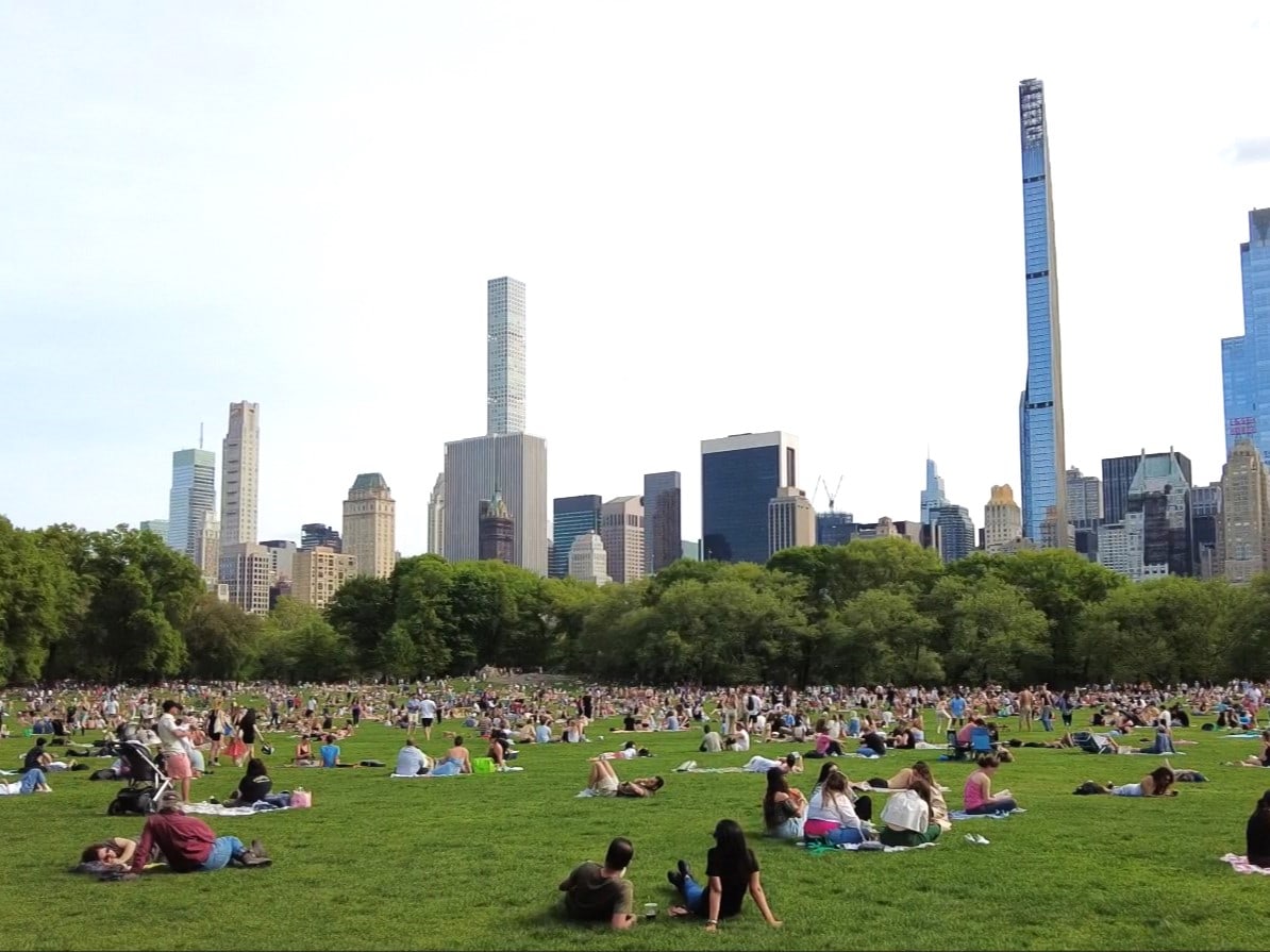 A group of people are sitting on the grass in central park.