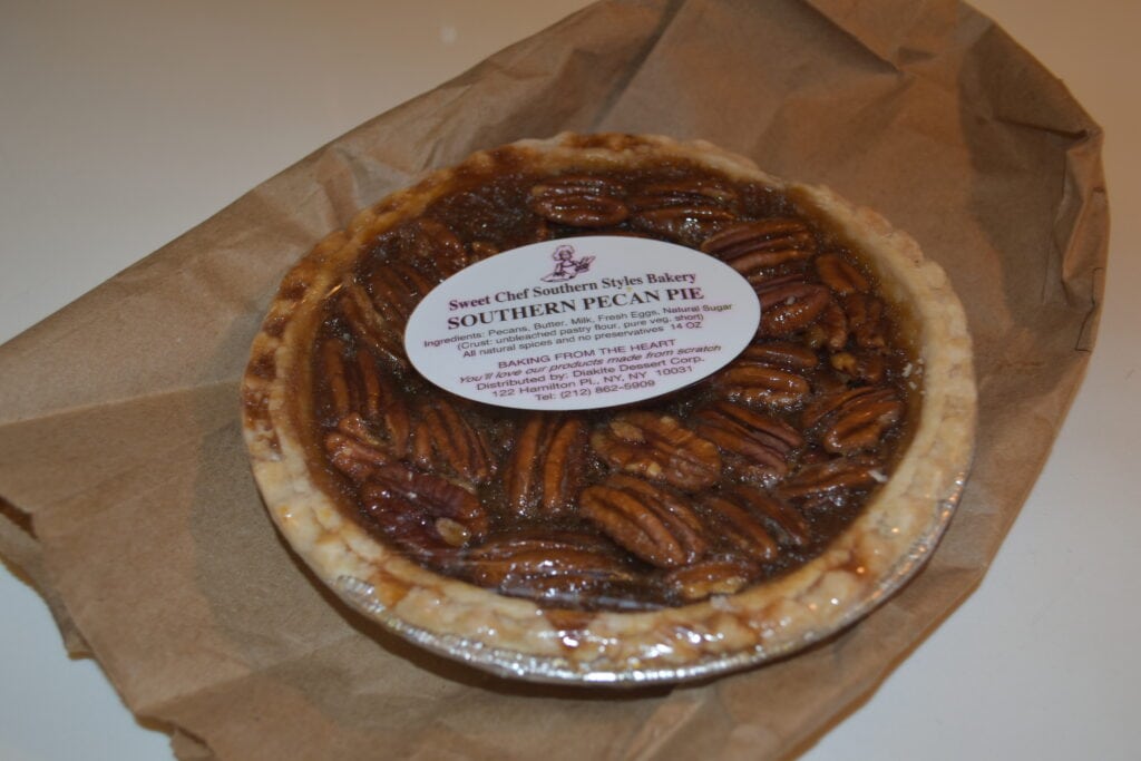 A southern pecan pie in clear packaging, labelled "Sweet Chef Southern Styles Bakery" on brown paper—a delicious taste of Food in New York.