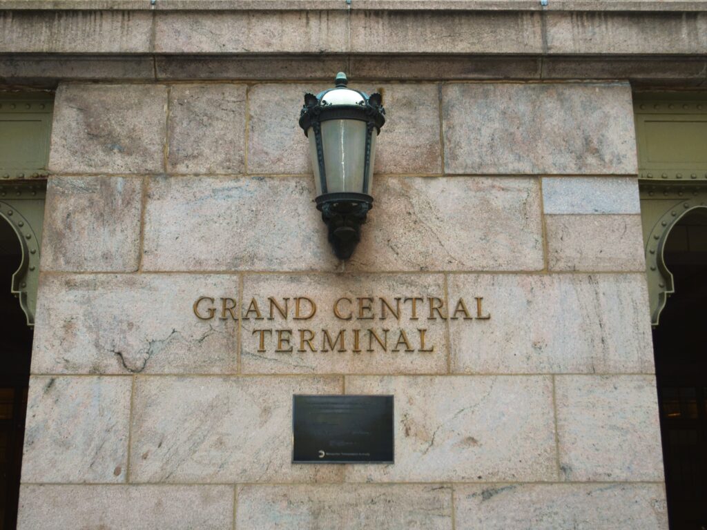 Stone wall with a lamp above the words "GRAND CENTRAL TERMINAL" in gold letters, capturing the iconic look of Grand Central station.