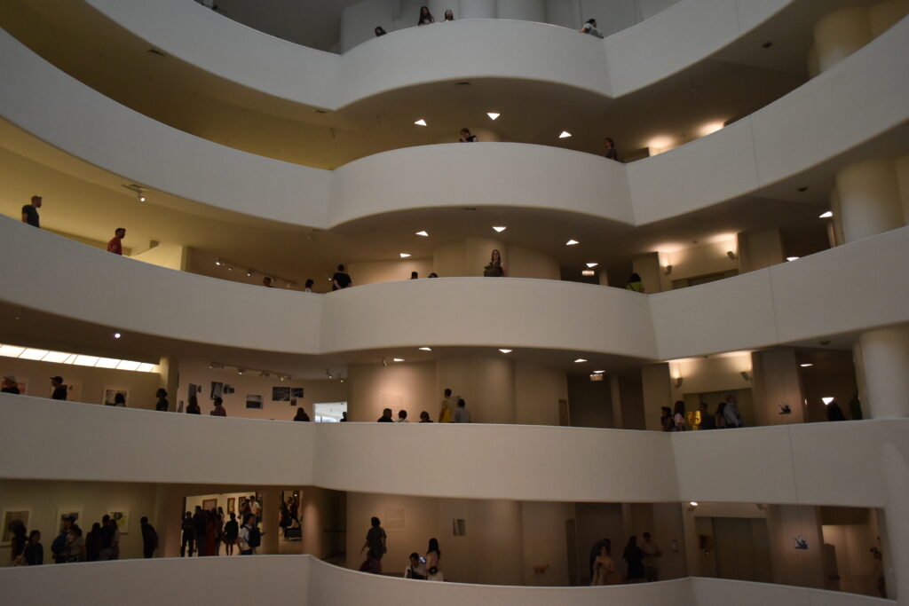 Visitors explore the multi-level interior of a modern, spiral-designed museum in New York, with open balconies offering sweeping views.