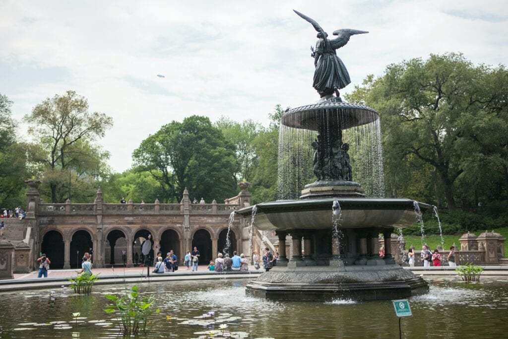 A statue of an angel in a fountain in central park.