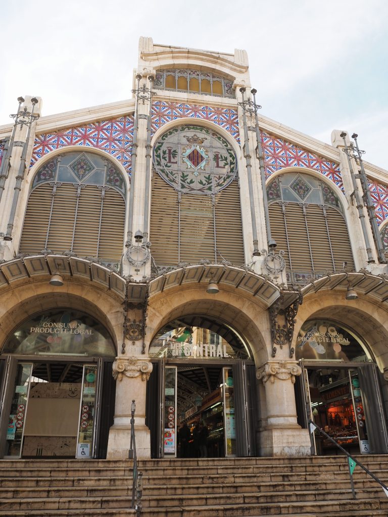 Ornate entrance of a historic market building with arched windows and decorative mosaic details above—one of the best things to do in Valencia for architecture lovers.