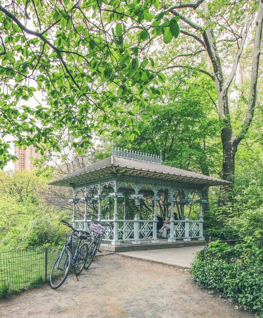 A gazebo in a park with bicycles parked in front of it.