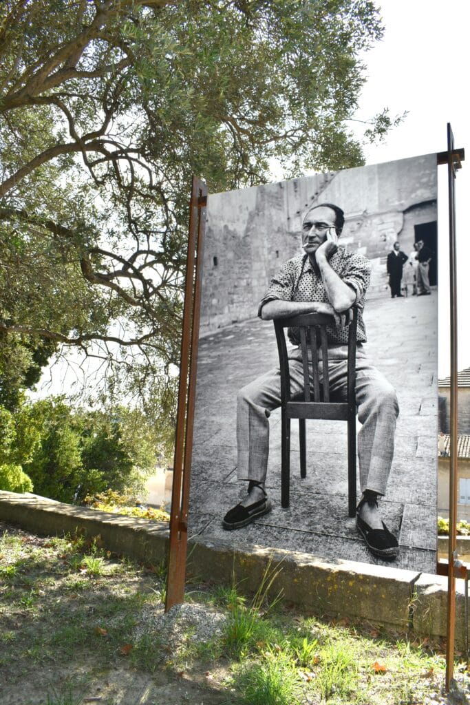 A black and white photo of a man sitting on a chair attraction Avignon