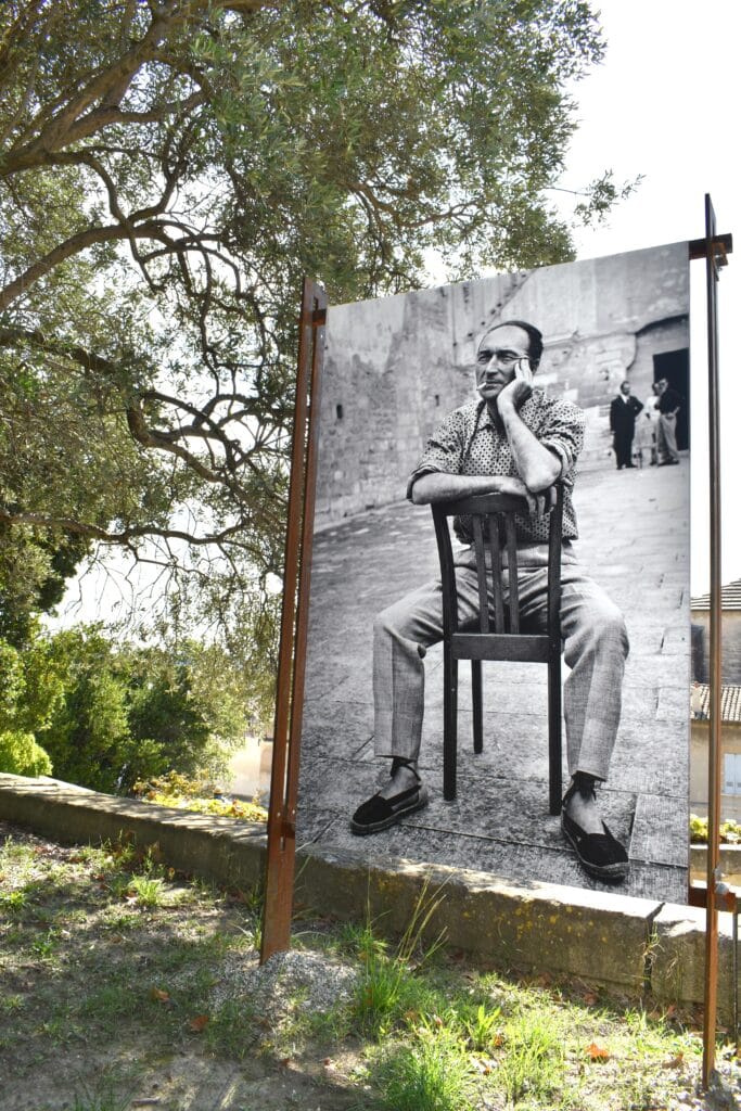 Large outdoor display of a black-and-white photo showing a man sitting backwards on a chair among trees—a striking sight when exploring the 5x Best things to Do in Avignon.