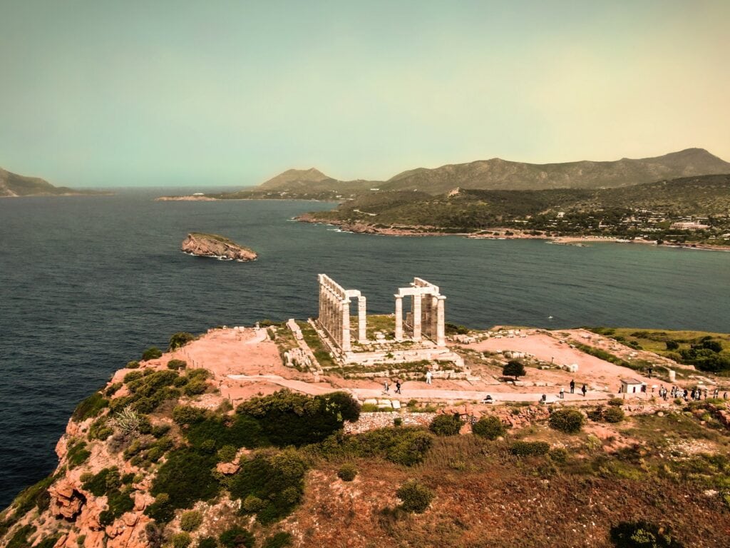 An aerial view of a temple on top of a hill overlooking the ocean.