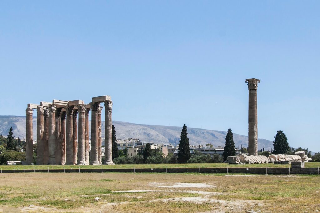 A group of pillars in a field with mountains in the background.