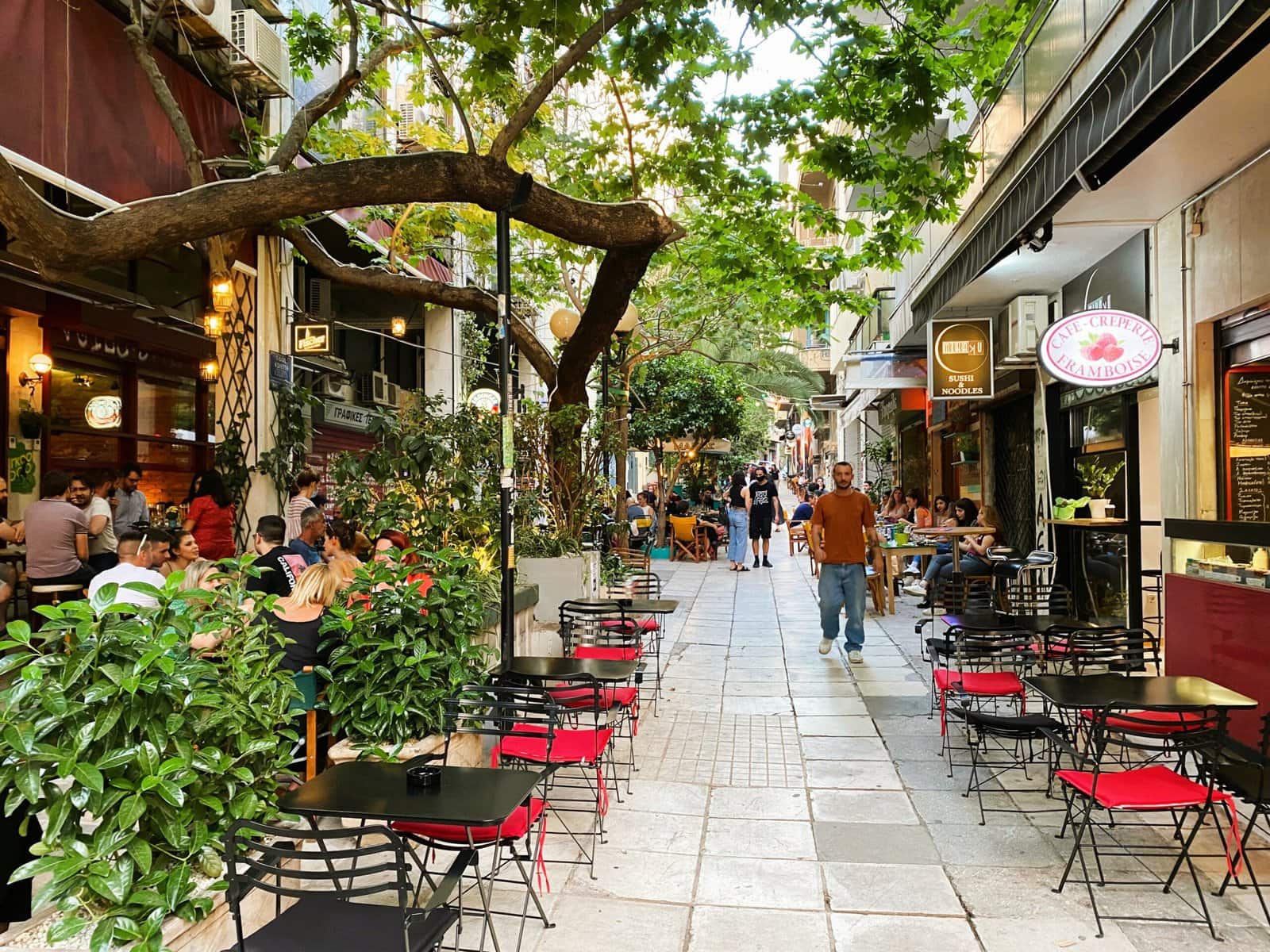 A street with tables and chairs and a tree.