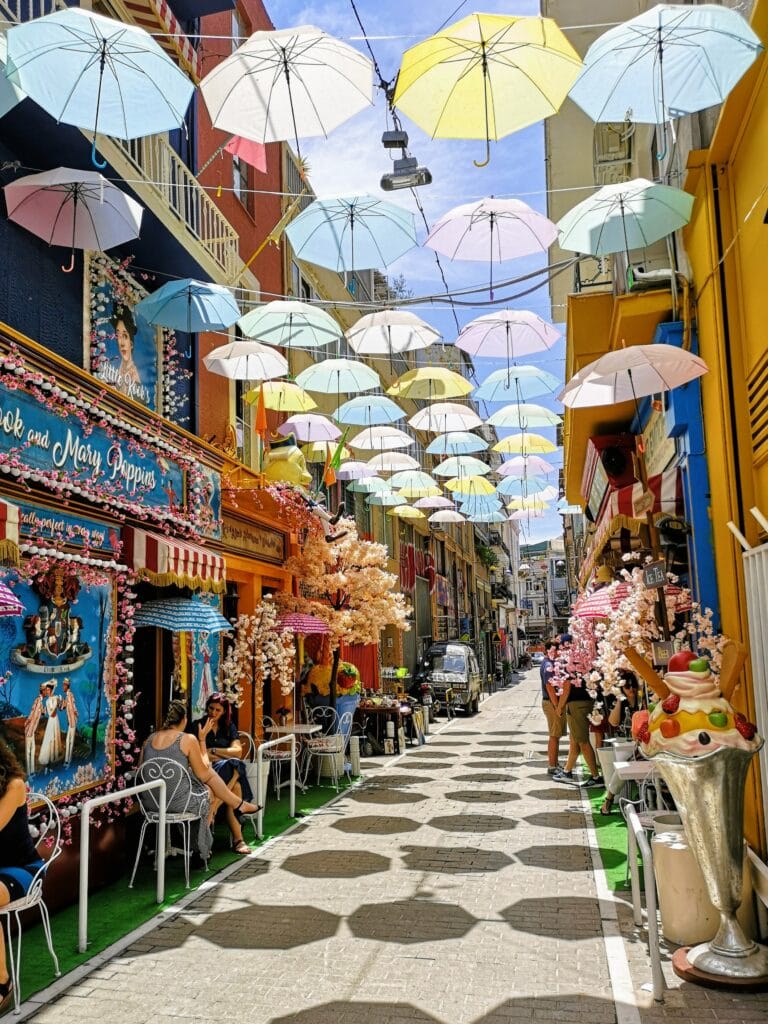 Colorful umbrellas hanging over a sidewalk.