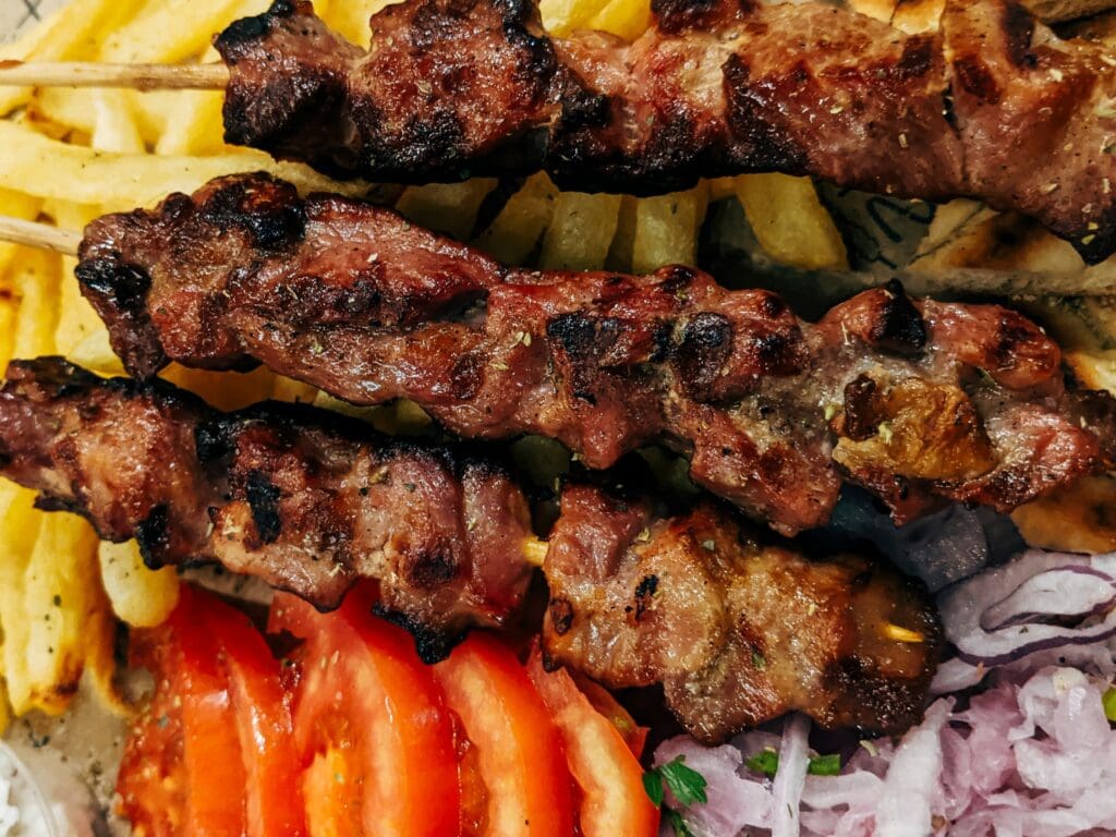 A plate of meat skewers and french fries.