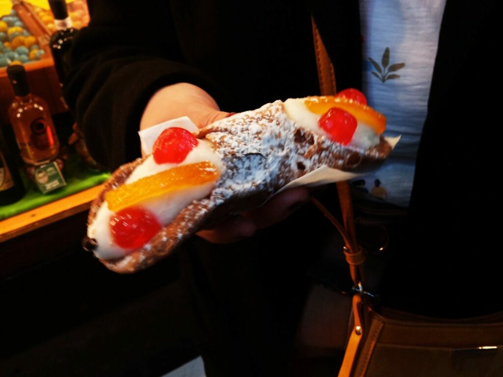 A person is holding the best Italian pastry with fruit on it in Rome.