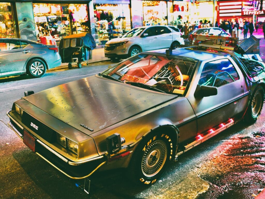 A silver DeLorean parked on a city street in New York.