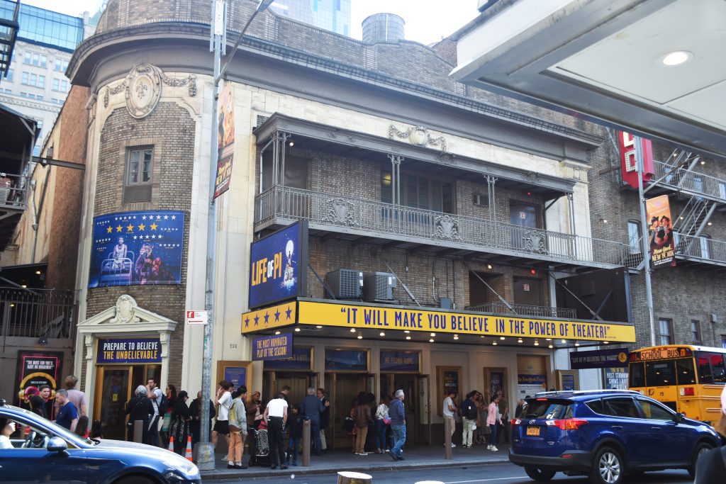 People enter a historic theater with a marquee that reads, "It will make you believe in the power of theater"—one of the 12x best attractions in New York City (Updated 2025).