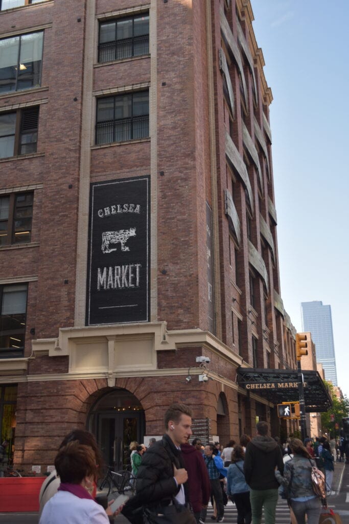 People walk near the entrance of Chelsea Market, a large brick building and one of 12x The best attractions in New York City (Updated 2025).