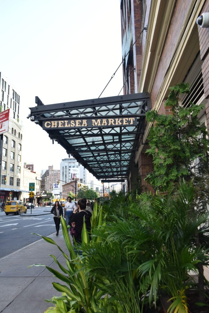 Awning with "Chelsea Market" sign above a busy pavement and street, with plants in the foreground—one of 12x The best attractions in New York City (Updated 2025).