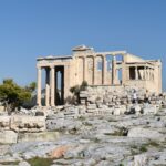 Ancient Greek ruins of the Erechtheion temple on the Acropolis of Athens, with clear blue skies in the background.