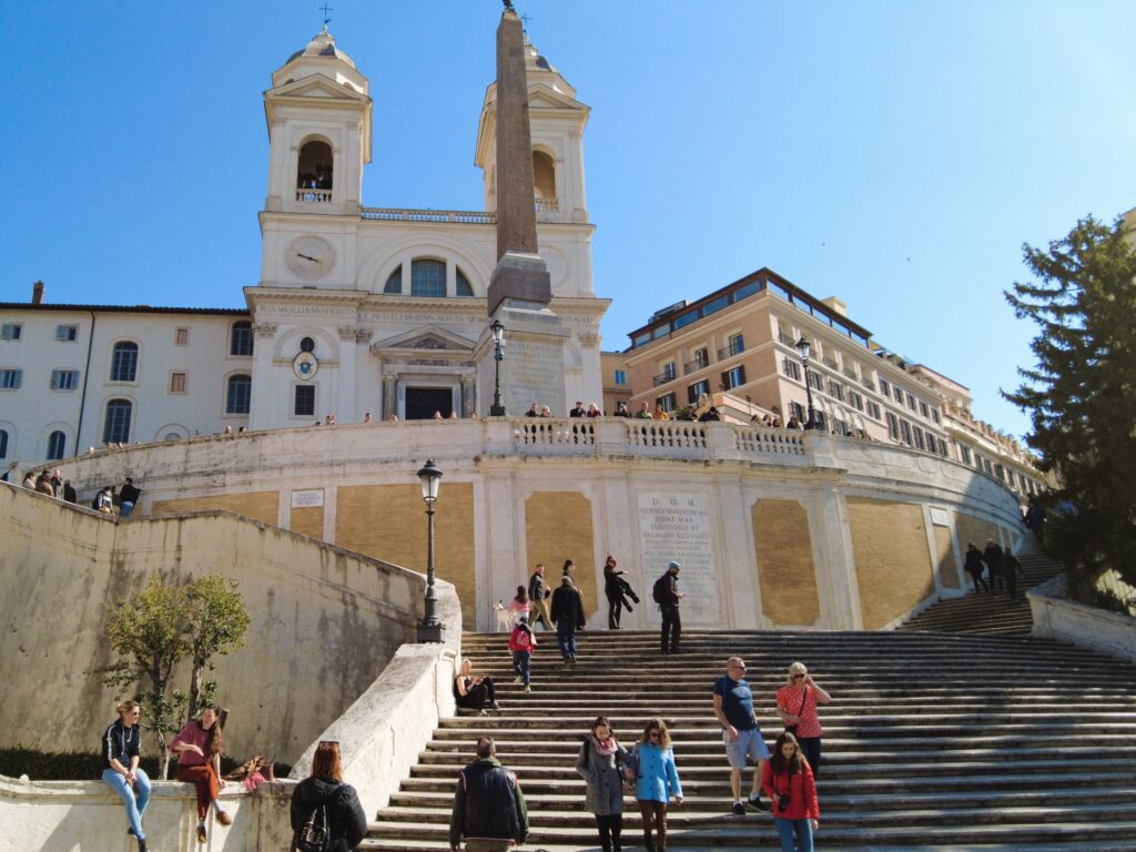 The Spanish Steps, a must-see attraction in Rome, bustle with people against the backdrop of the Trinità dei Monti church.