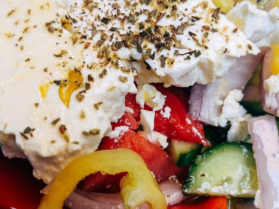 A plate of greek salad with cucumbers, tomatoes and feta cheese.