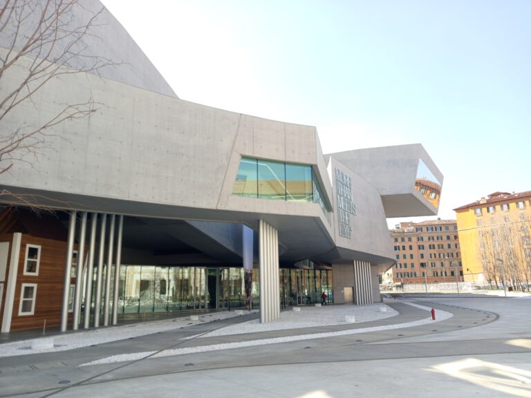 Discover the modern concrete building with large glass windows and geometric shapes, echoing the architectural brilliance of the MAXXI museum in Rome, set seamlessly in an urban environment.