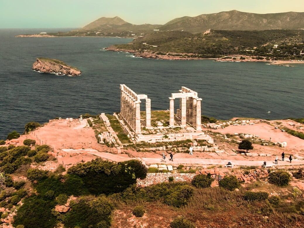 An aerial view of a temple on top of a hill overlooking the ocean.