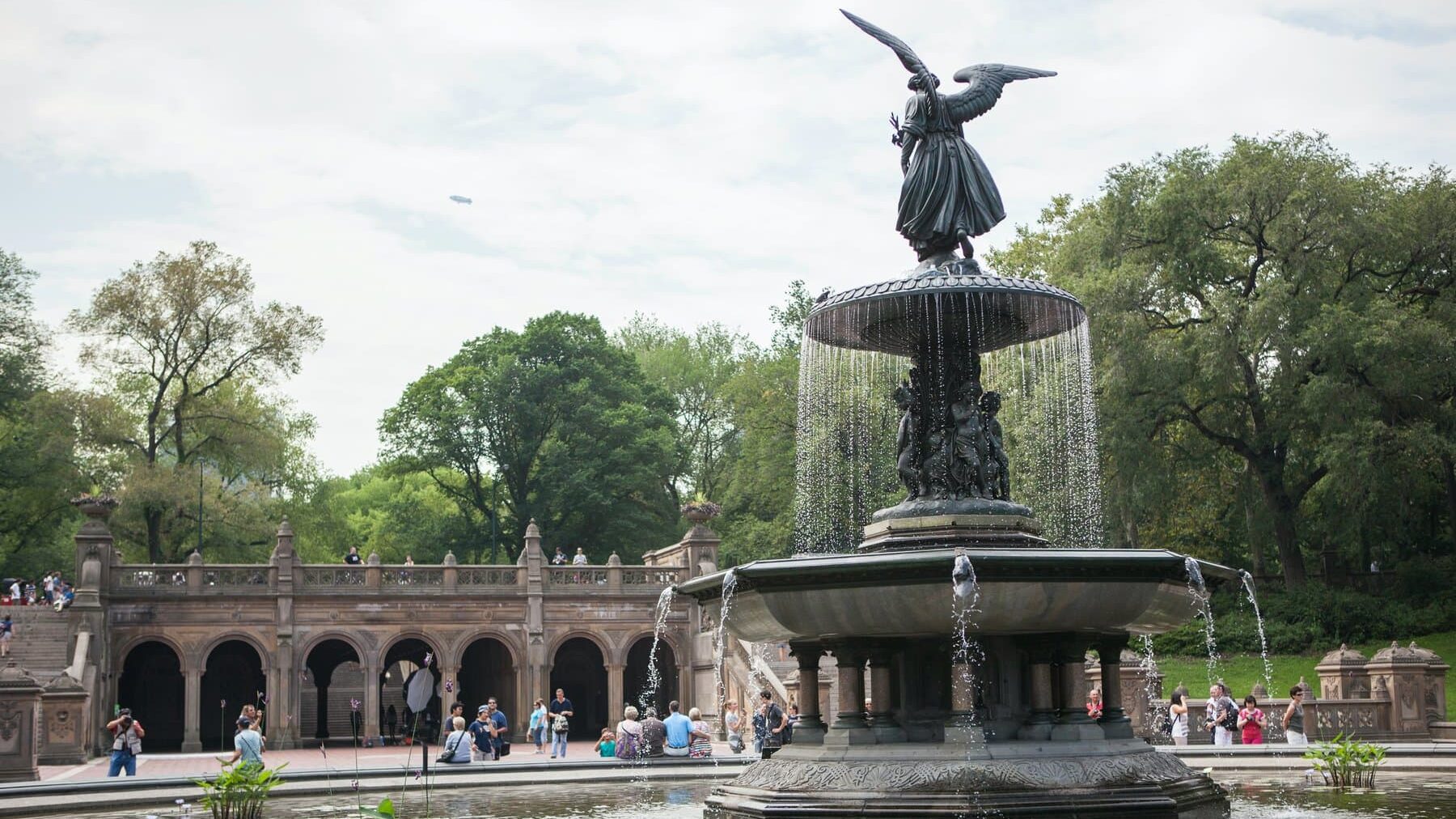 A statue of an angel in a fountain in central park.