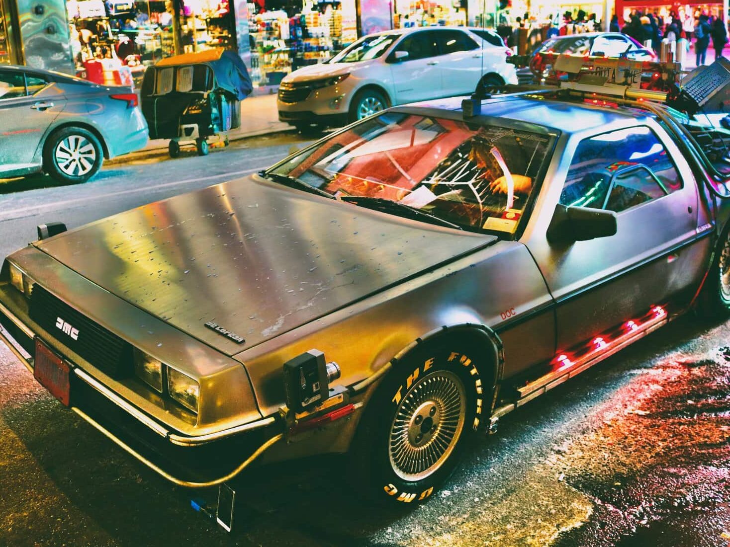 A silver DeLorean parked on a city street in New York.