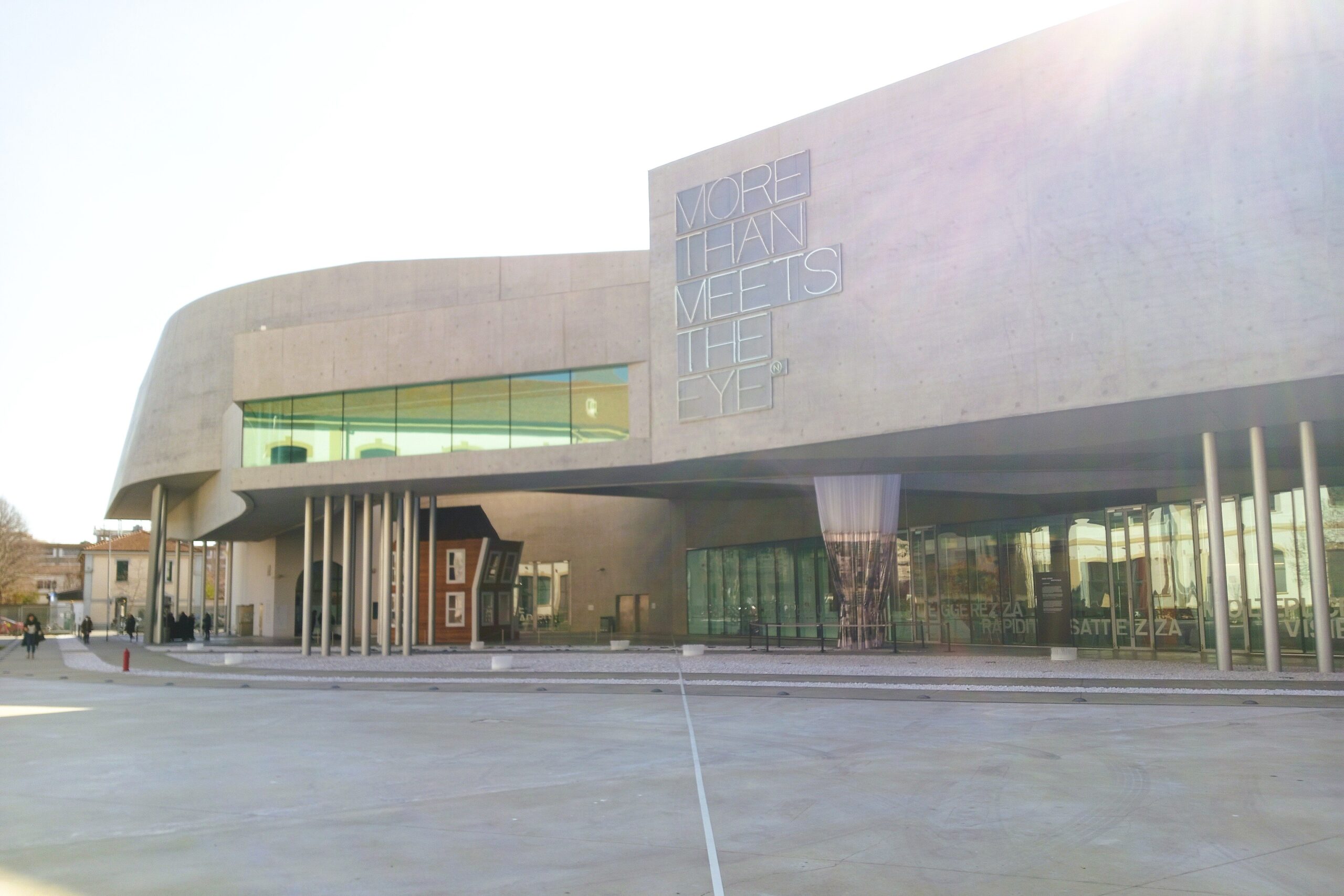 Modern building with large curved facade and glass windows, featuring the text "More Than Meets the Eye." A must-visit for those exploring Rome, reminiscent of the architectural wonders at MAXXI museum.