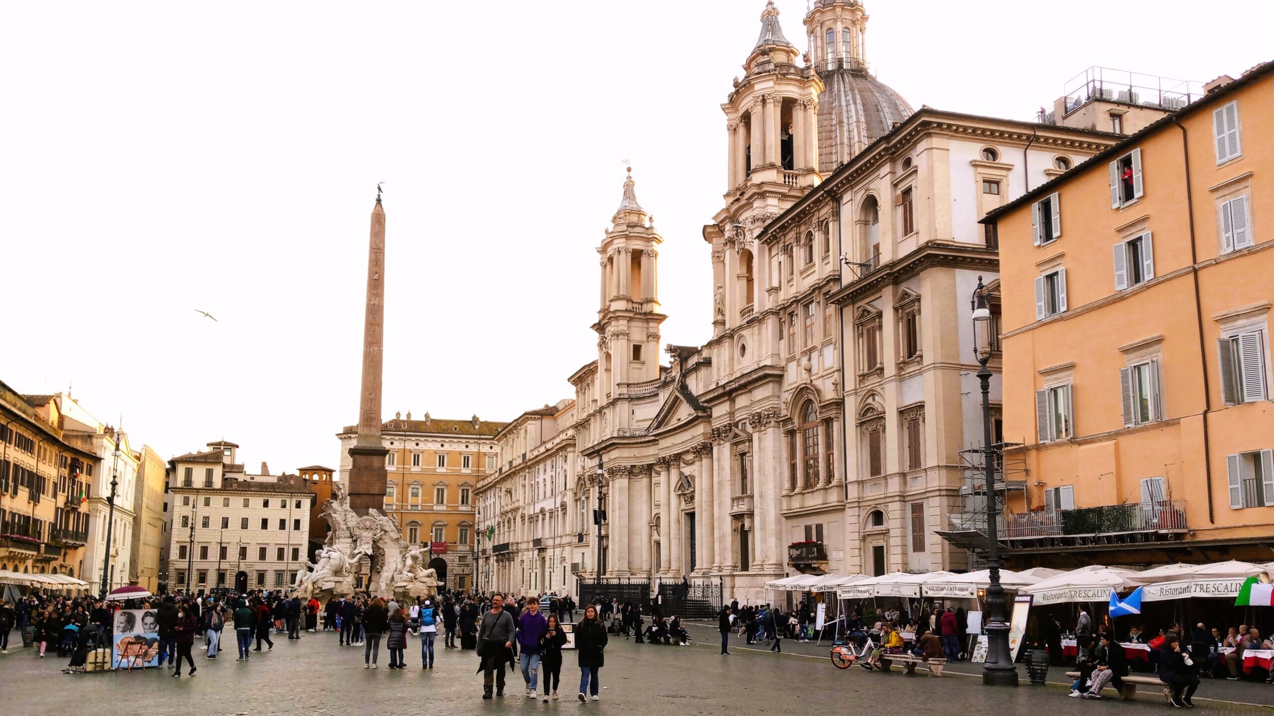 The bustling Piazza Navona in Rome, with its stunning fountains and Egyptian obelisk, showcases baroque architecture under a clear sky. A popular destination nestled in one of the city's most vibrant neighborhoods.