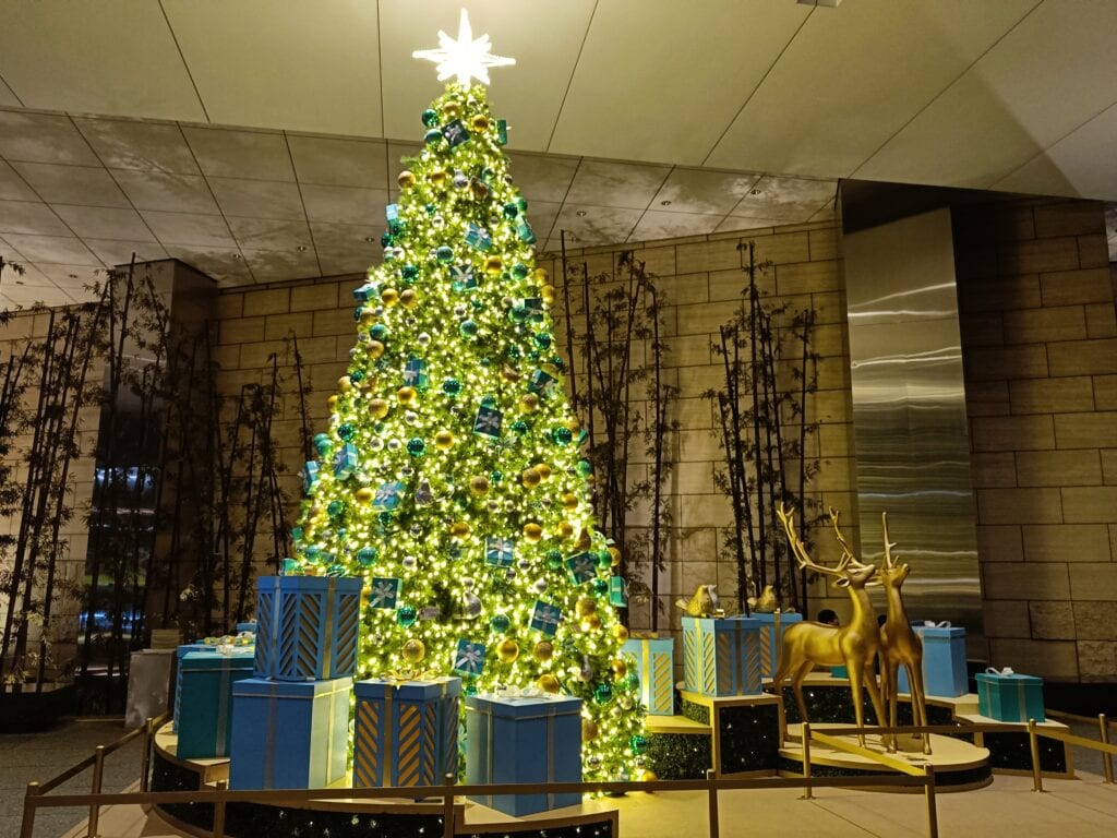 A tall Christmas tree with gold and blue baubles, surrounded by wrapped presents and two golden reindeer, creates a magical Rome-inspired setting perfect for festive dates.