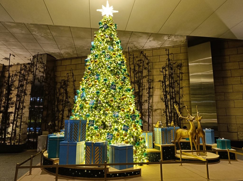 A decorated Christmas tree with blue gifts and golden reindeer in an indoor setting, evoking the charm of festive dates Rome is known for.