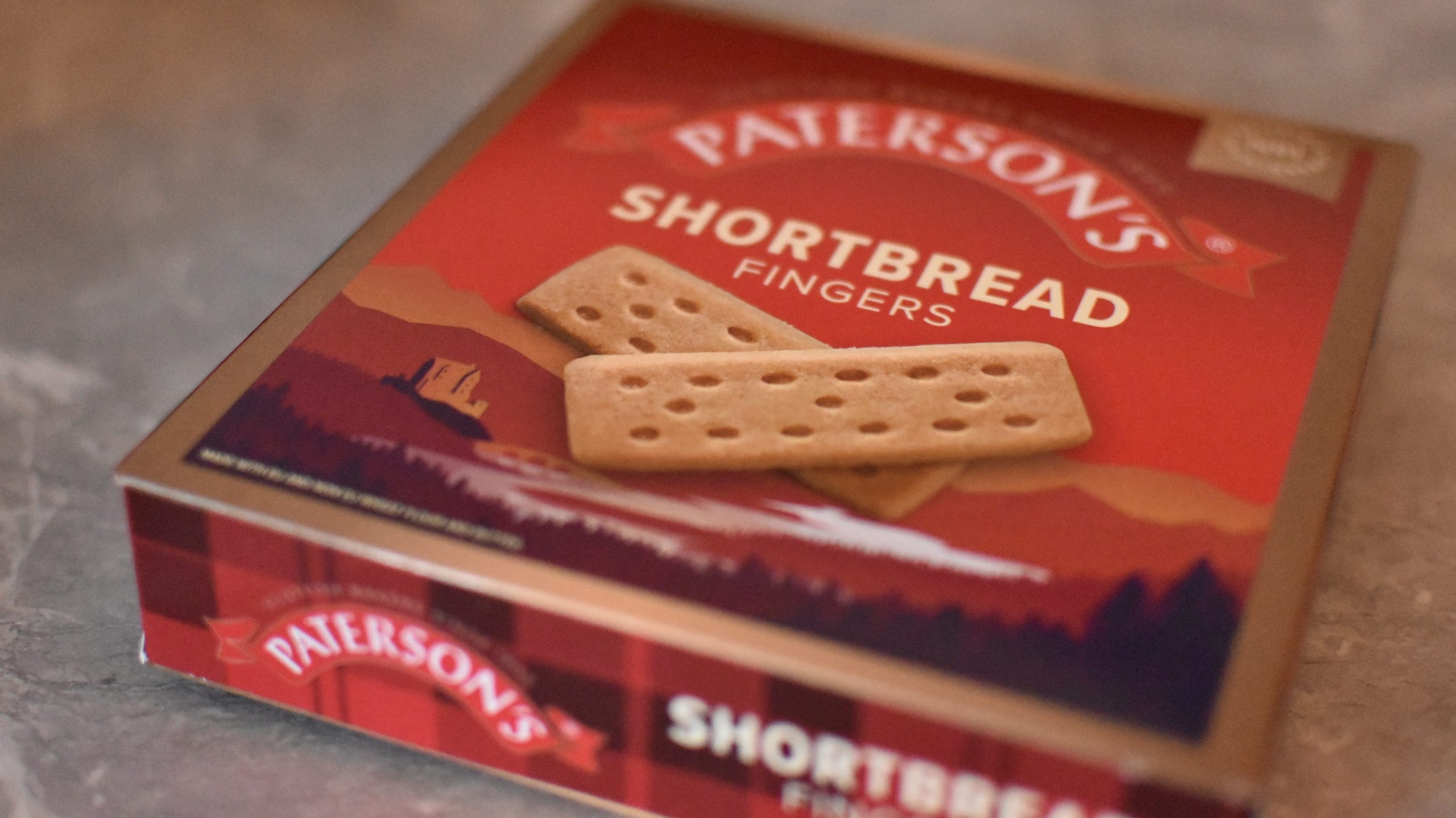 A box of Paterson’s Shortbread Fingers, a classic choice for food souvenirs Glasgow, sits on a gray surface.