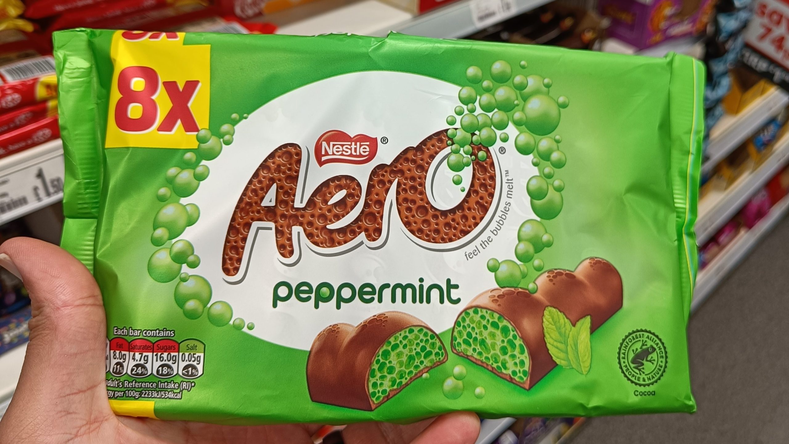 A hand holding an 8-pack of Nestlé Aero peppermint chocolate bars in a store candy aisle—one of the best food souvenirs from Glasgow.