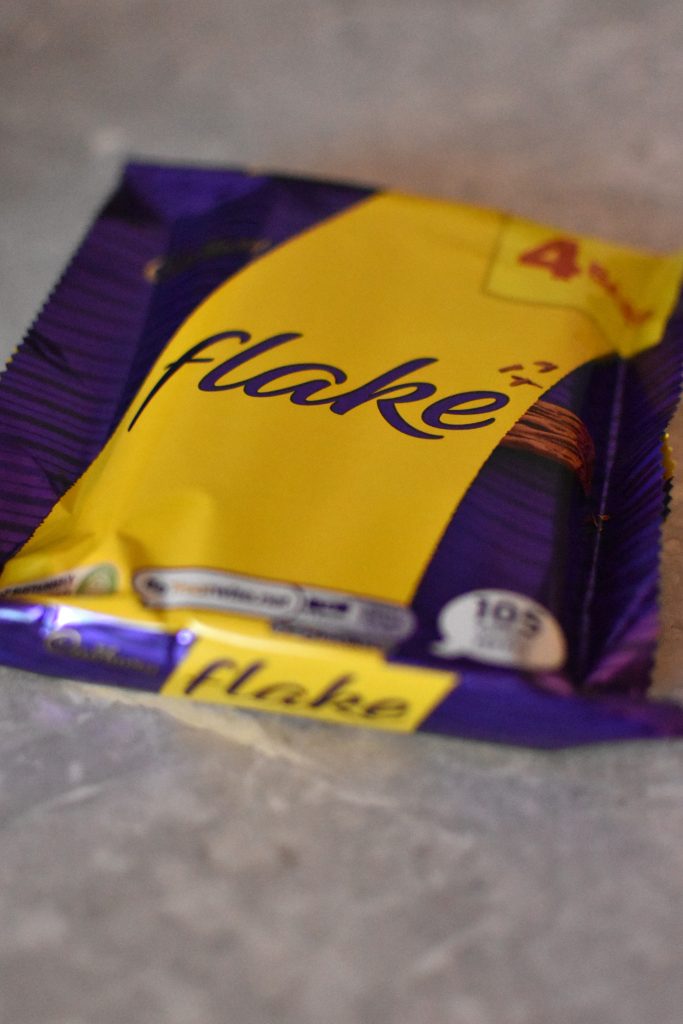 A wrapped Cadbury Flake chocolate bar lies on a gray surface—one of the best food souvenirs from Glasgow.