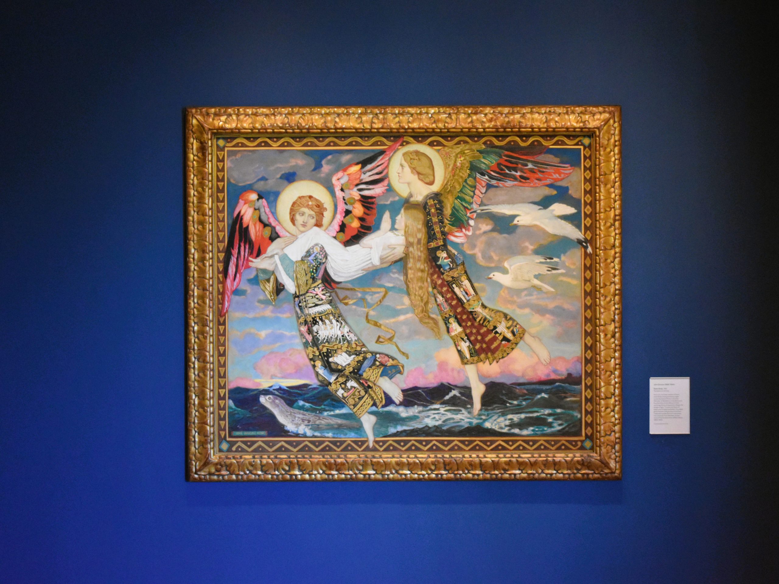 A framed painting of two angels in colorful robes flying above waves, displayed on a blue wall—reminiscent of masterpieces found in the best museums Edinburgh has to offer.