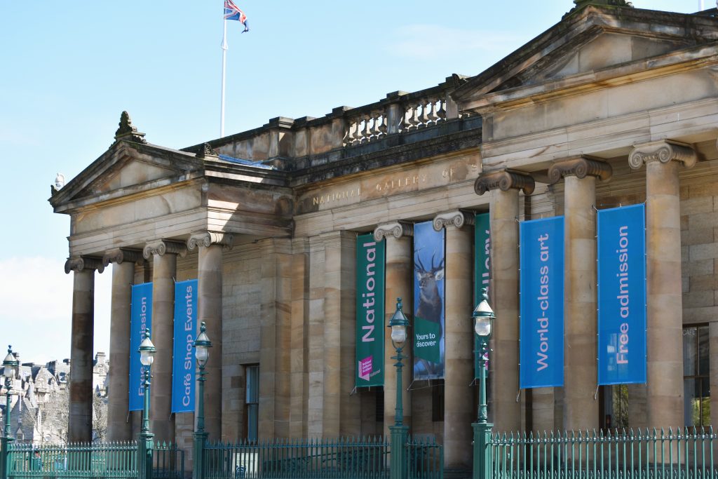 Neoclassical museum building with columns, banners, and a UK flag, reading "National Gallery of Scotland," one of the best museums Edinburgh has to offer.