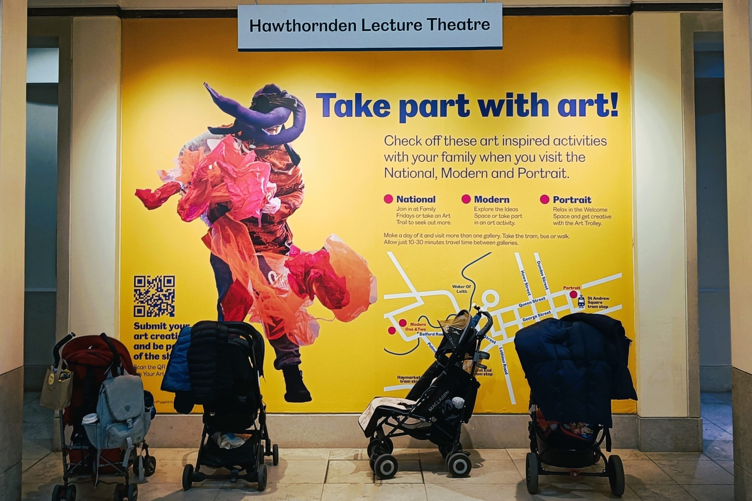 Four strollers are parked in front of a bright yellow art activity sign at Hawthornden Lecture Theatre, one of the highlights at one of the best museums Edinburgh has to offer.