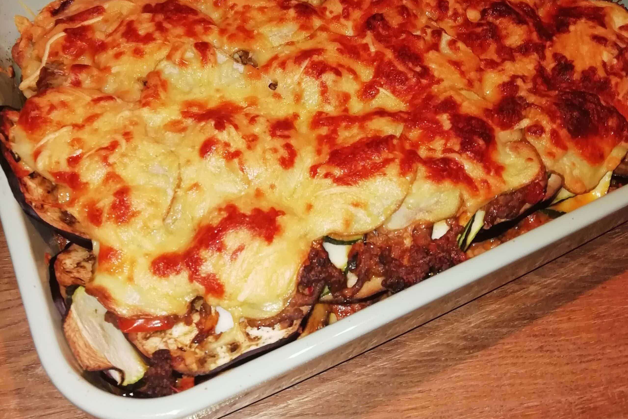 A baked casserole dish with golden, melted cheese on top of layered vegetables and meat sauce—a must-try Greek food and one of the best comfort foods Athens has to offer.