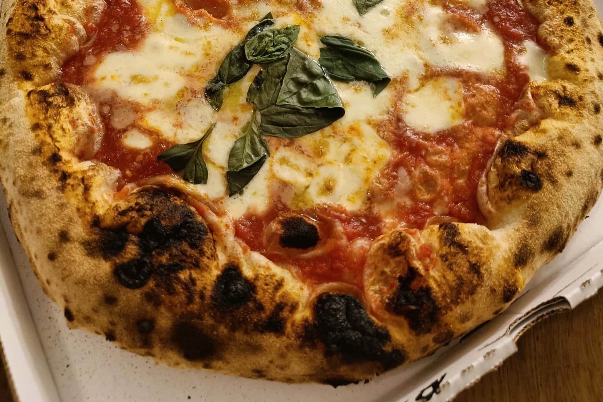 A close-up of a Margherita pizza with melted cheese, tomato sauce, and fresh basil leaves.