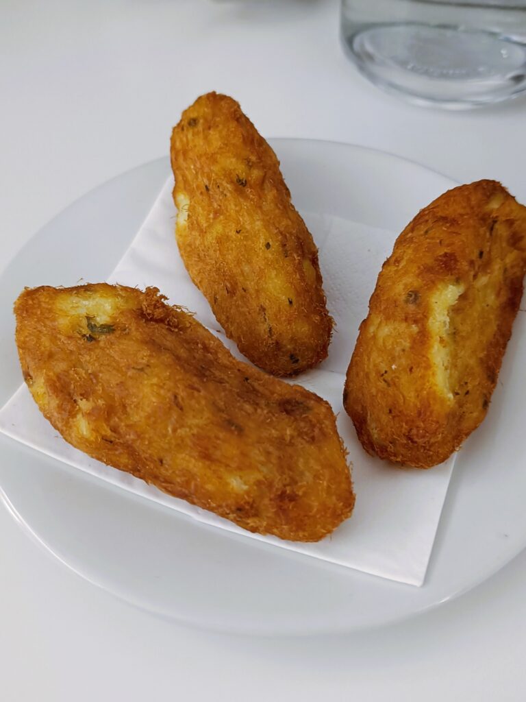 Three golden-brown fried croquettes on a white plate with a serviette underneath—a tasty treat you might find whilst exploring popular attractions in Porto.