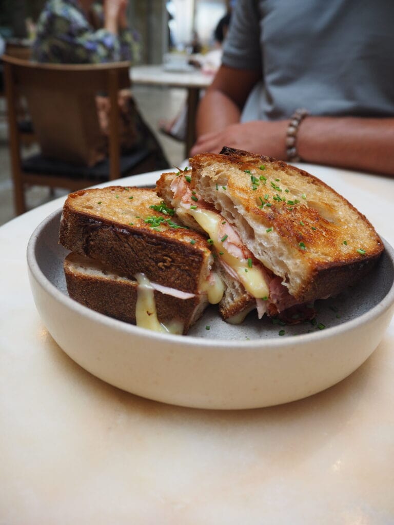 Grilled ham and cheese toastie on a plate, with melted cheese, in a cosy restaurant—a delicious option if you're wondering where to eat in Porto.