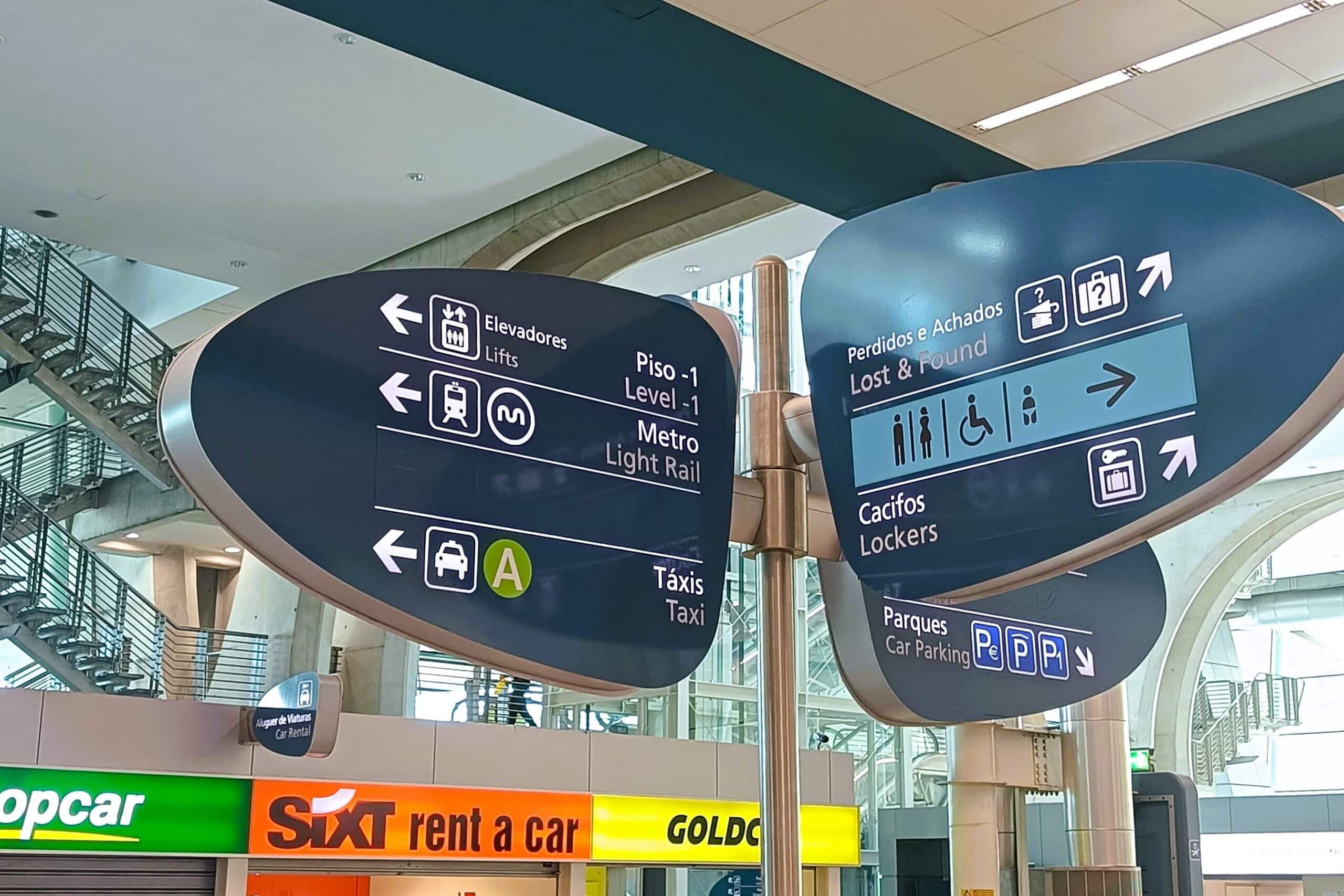 Airport signs showing directions for lifts, metro, taxi, lost property, lockers, and car parking above hire counters make getting around Porto easy for travellers.