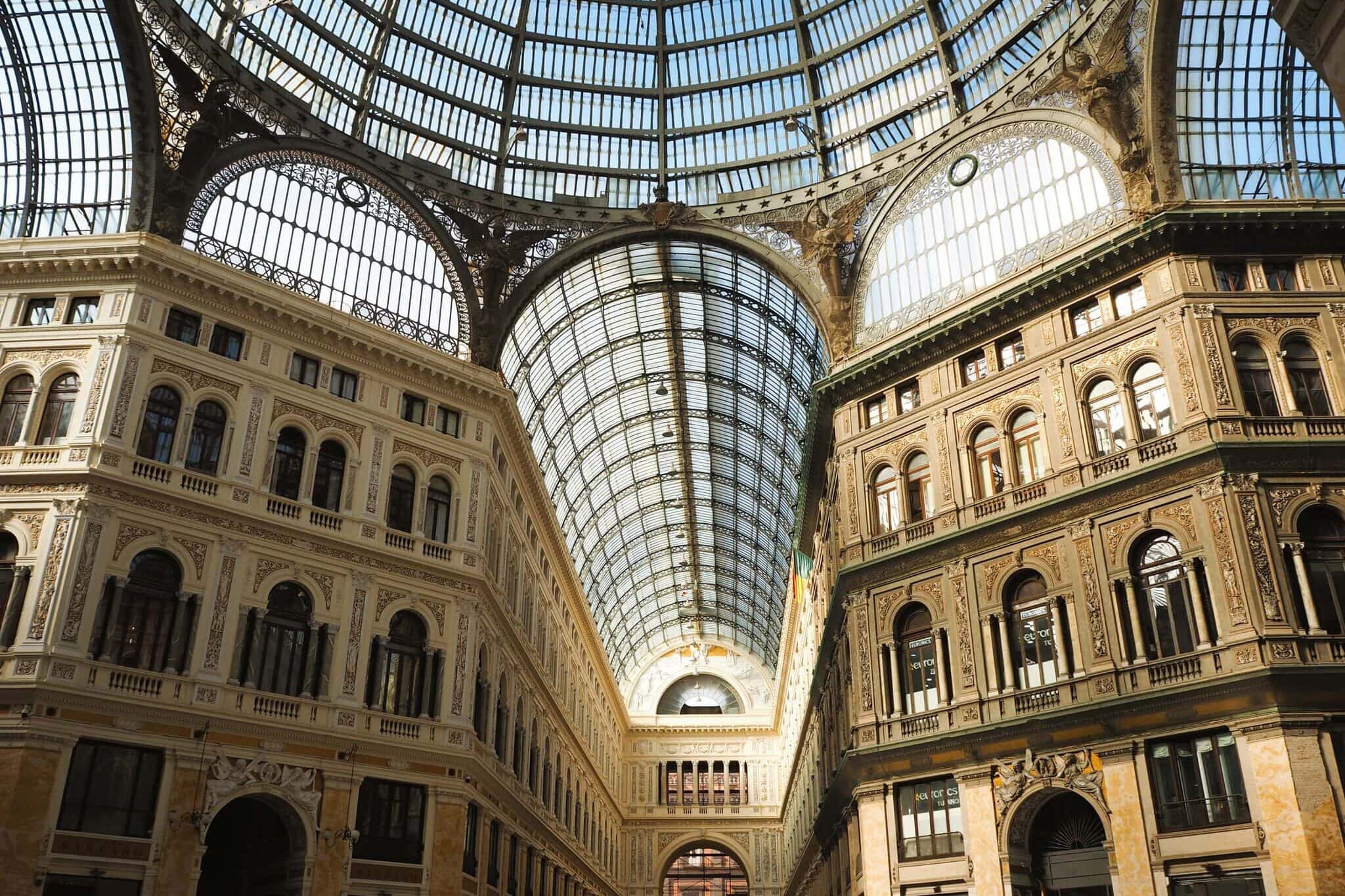 Interior view of a grand building with a glass-domed ceiling and ornate architectural details.