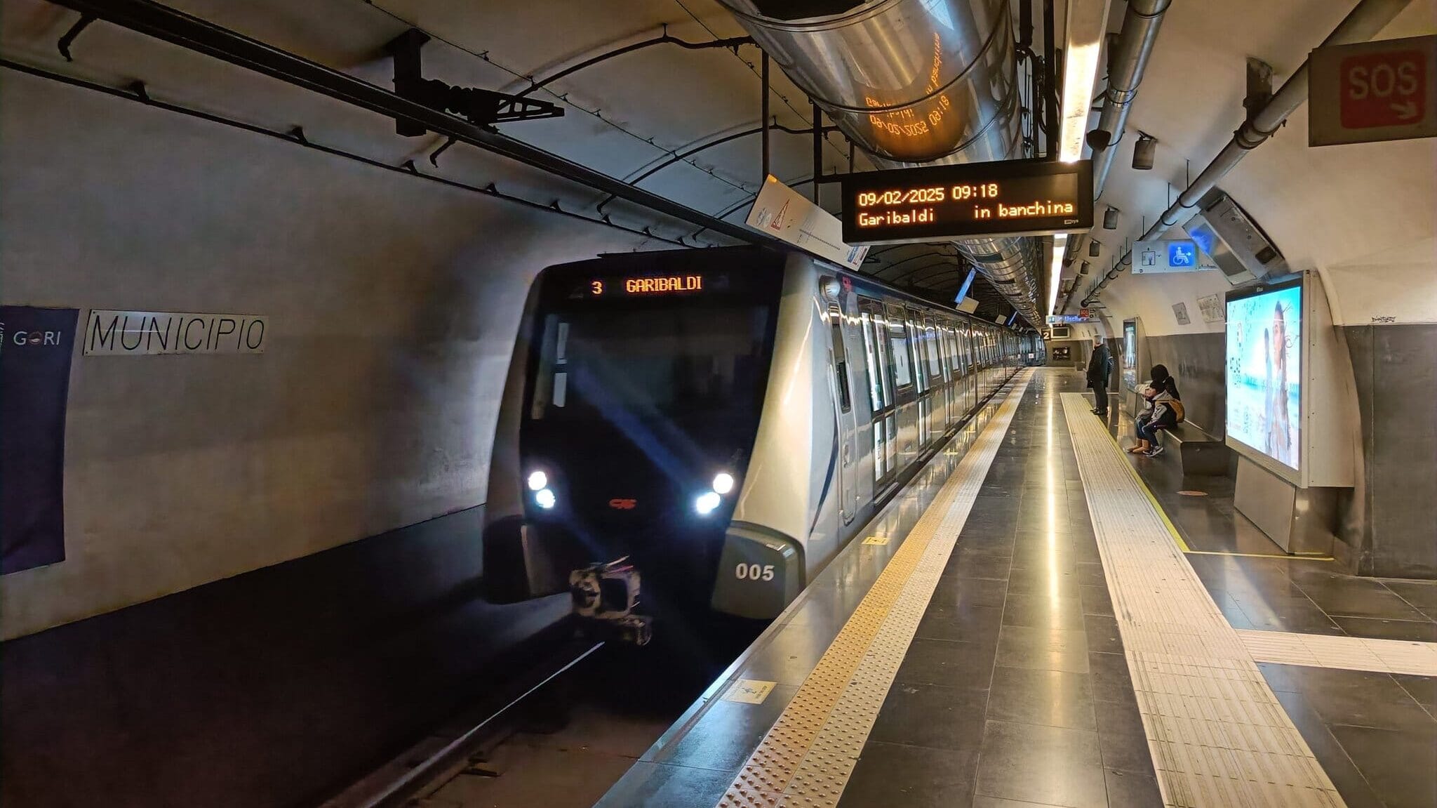 A subway train arrives at Municipio station with a few people waiting on the underground platform—a perfect local scene to discover in The Ultimate Naples City Guide (2026 Trip Planner).