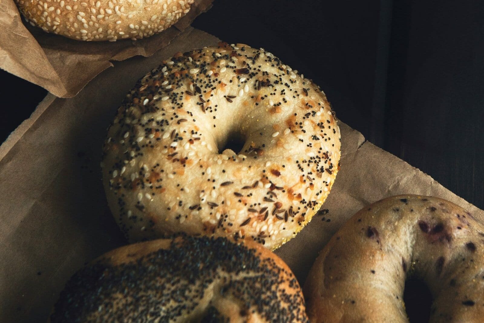 Assorted bagels with different toppings on brown paper, including sesame seeds, poppy seeds, and everything seasoning—New York insider tips for the best bagel experience.
