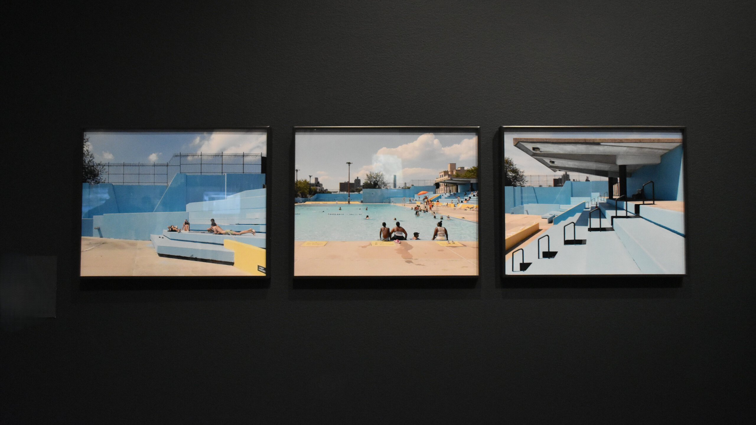 Three framed photographs of an empty outdoor swimming pool are displayed on a dark grey wall—discover similar striking works when you visit MoMA in New York (Museum of Modern Art).