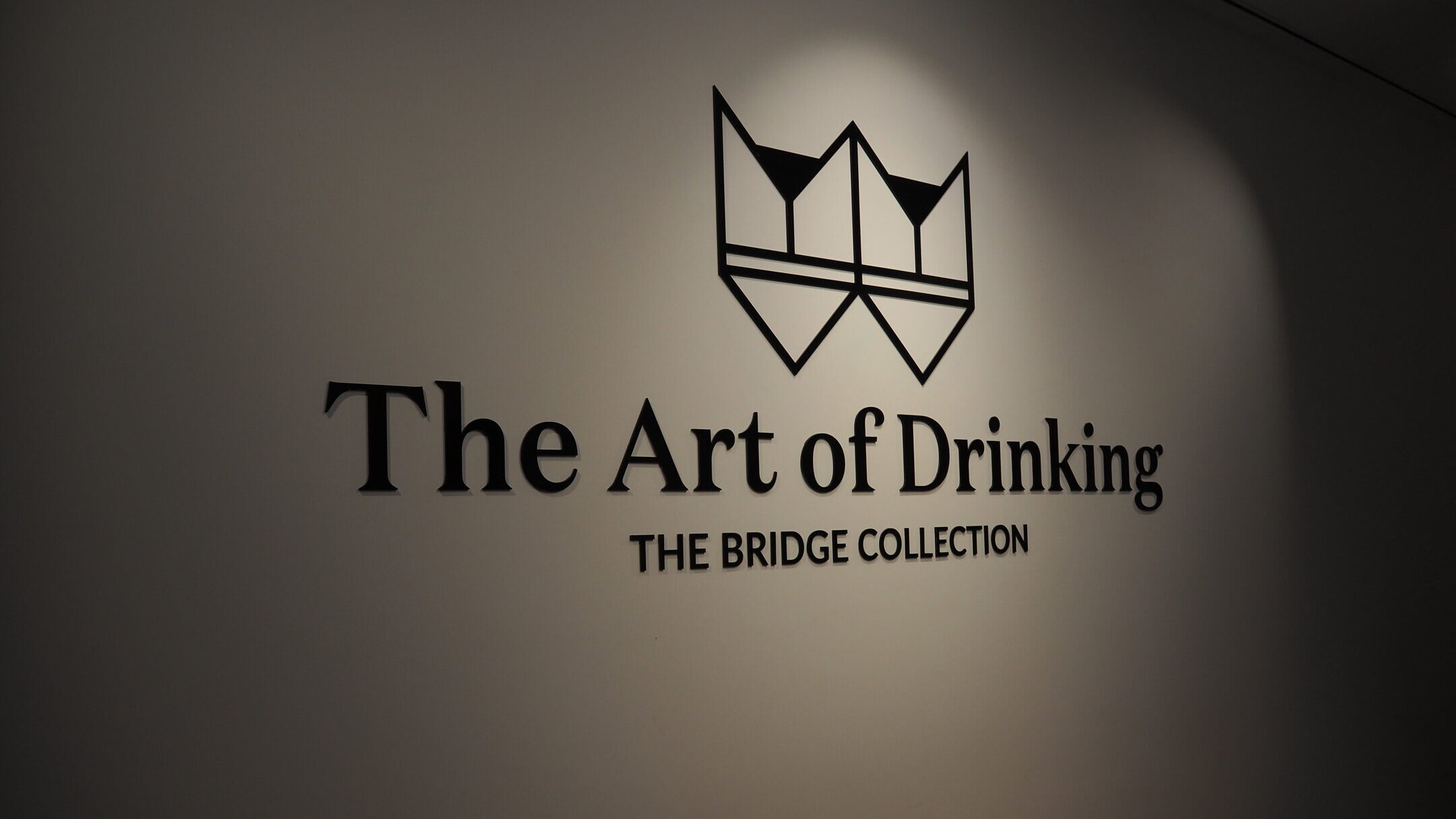 Wall sign at WOW Porto reads "The Art of Drinking, THE BRIDGE COLLECTION" with a minimalist logo above the text, capturing the essence of the World of Wine Porto experience.