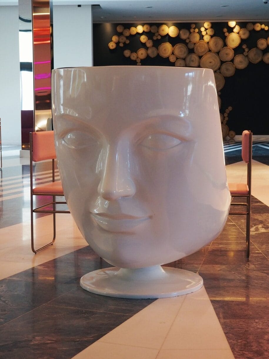 Large white chair shaped like a human face stands in a modern, stylish room with art and geometric floors, echoing the unique design flair found at WOW Porto.