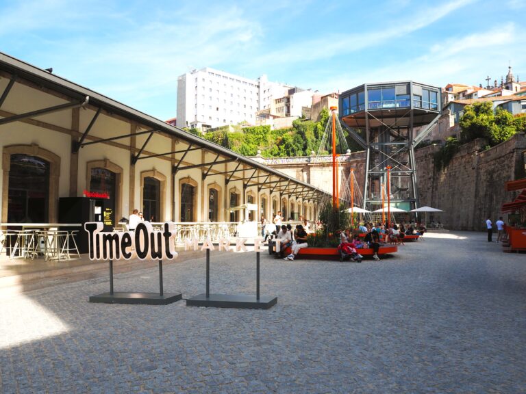 Outdoor courtyard of Time Out Market in Porto, where people relax among modern structures and old buildings—a vibrant spot that highlights why it’s considered one of the best markets among local food markets.
